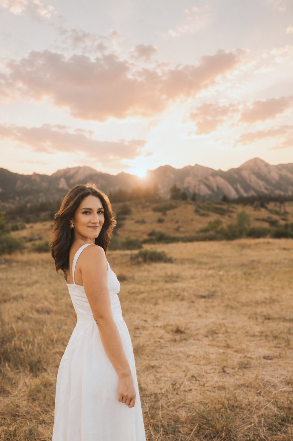 Tiffany Ramirez in a grass field at sunset, the Flatirons behind her.